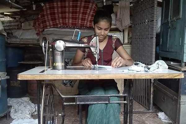 A young woman stitching masks.